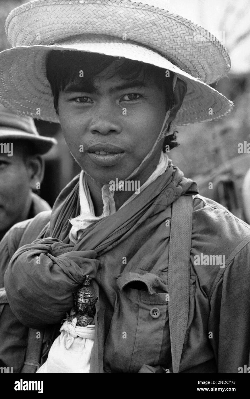 A Cambodian soldier wearing two looted straw hats on his head and has a ...