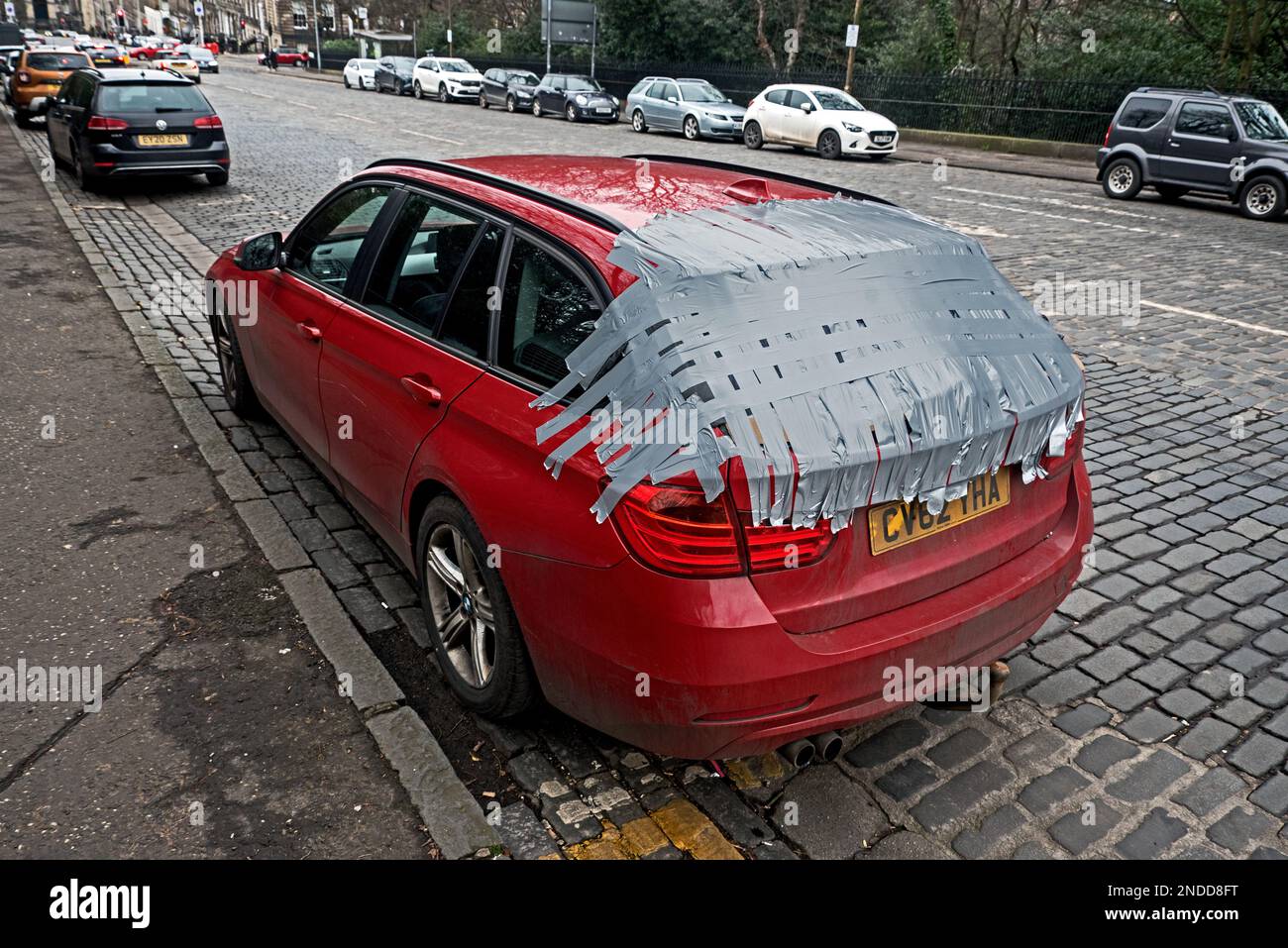Voiture avec fenêtre arrière cassée patchée avec ruban adhésif dans la nouvelle ville d'Édimbourg. Banque D'Images