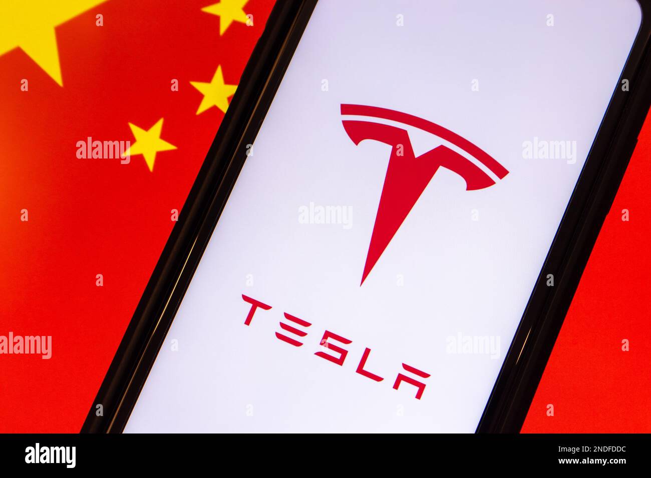 Vancouver, CANADA - février 15 2023 : logo de la multinationale américaine de l'automobile, de l'IA et de l'énergie durable Tesla vu dans smartphone, sur le drapeau chinois Banque D'Images