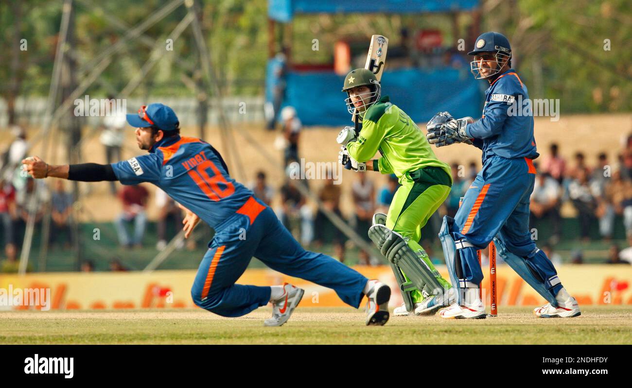 India's Virat Kohli, left, catches a ball to dismiss Pakistan's Umar Amin as Indian wicketkeeper Mahendra Singh Dhoni, right, looks on during their fourth Asia Cup cricket match in Dambulla, Sri Lanka, Saturday, June 19, 2010. (AP Photo/Eranga Jayawardena) Banque D'Images