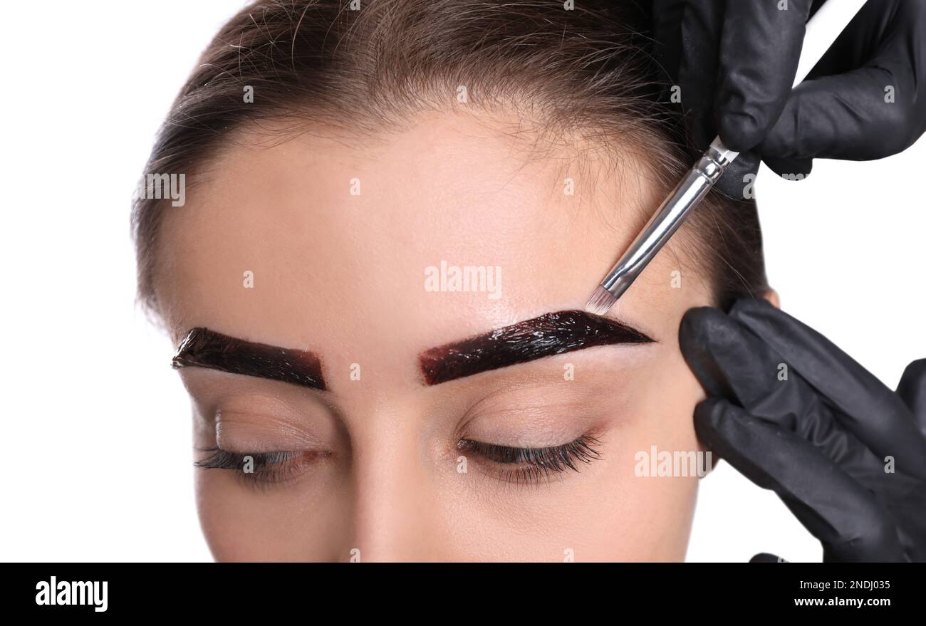 Esthéticienne appliquant la teinte pendant la procédure de correction des sourcils sur fond blanc, gros plan Banque D'Images