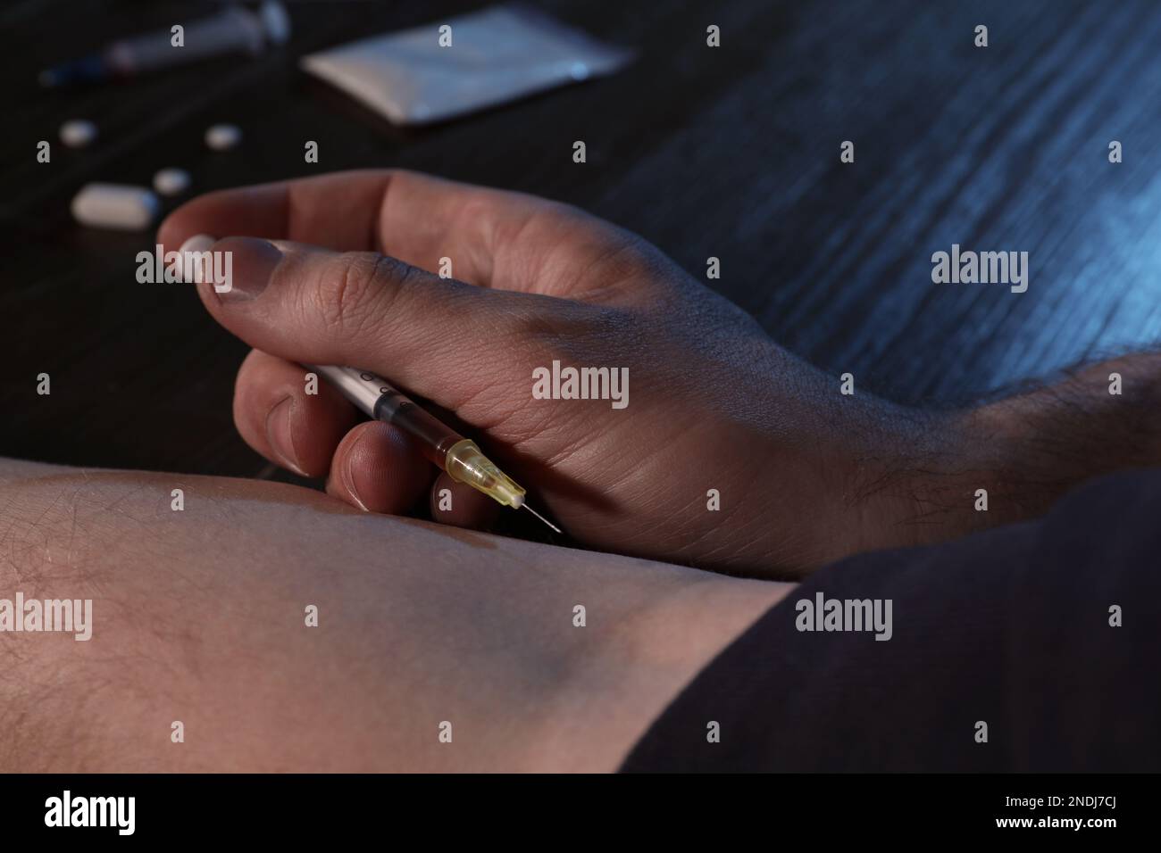 Homme accro prenant des médicaments à la table, gros plan Banque D'Images