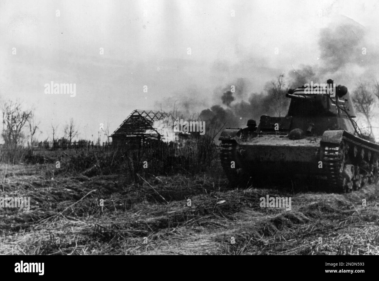 Un modèle de char soviétique T 26 C capturé de 1937 avec des marques allemandes de la SS Panzer Division 'Totenkopf' de 3rd traverse un village en feu près du lac Ilmen. Banque D'Images