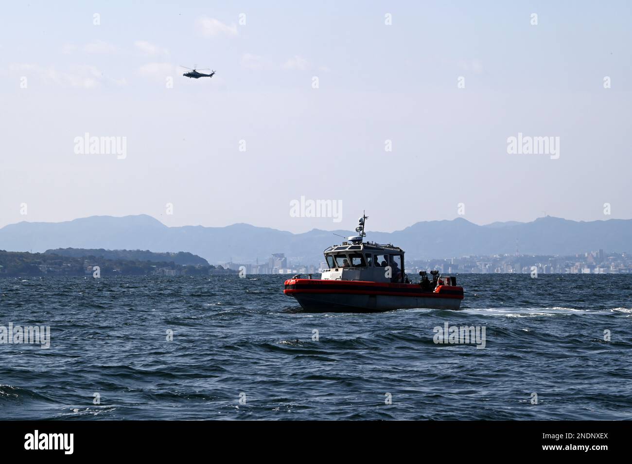 L'équipage à bord des États-Unis Le petit bateau intercepteur à longue portée de 35 pieds du Cutter Kimball (WMSL 756) de la Garde côtière se prépare à effectuer un exercice conjoint de recherche et de sauvetage dans la baie Kagoshima, au Japon, avec un équipage d’hélicoptère AgustaWestland AW139 de la Garde côtière japonaise, le 14 février 2023. L’équipage de Kimball est à Kagoshima pour mener une formation conjointe et des échanges professionnels avec les membres de la Garde côtière japonaise, en développant un protocole de coopération signé en 2022 entre les deux services maritimes, qui a établi l’opération SAPPHIRE, une opération perpétuelle visant à renforcer les relations, à accroître les engagements bilatéraux, an Banque D'Images