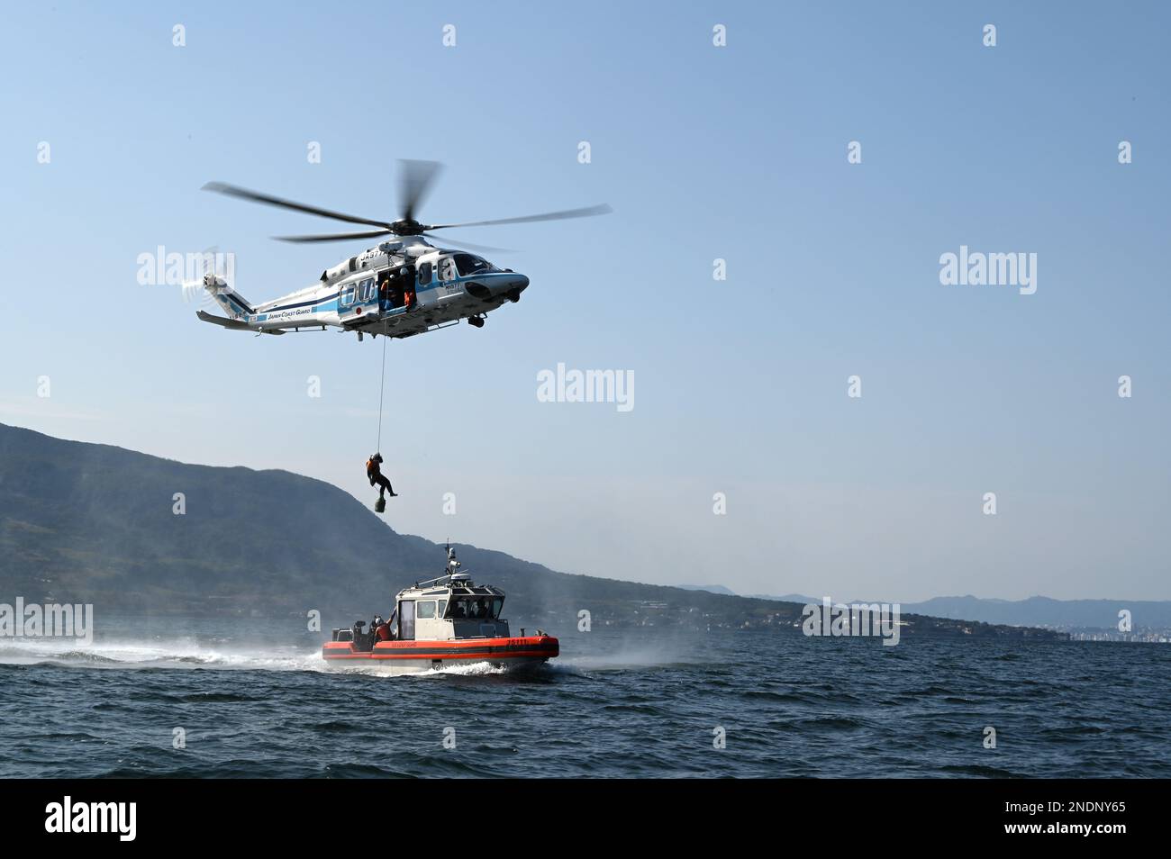 Un technicien de sauvetage mobile de la Garde côtière japonaise se reporte d'un hélicoptère AgustaWestland AW139 de la Garde côtière japonaise vers les États-Unis Petit bateau intercepteur à longue portée de 35 pieds de Kimball’s (WMSL 756) lors d’un exercice conjoint de recherche et de sauvetage dans la baie Kagoshima (Japon), le 14 février 2023. L’équipage de Kimball est à Kagoshima pour mener une formation conjointe et des échanges professionnels avec les membres de la Garde côtière japonaise, en développant un protocole de coopération signé en 2022 entre les deux services maritimes, qui a établi l’opération SAPPHIRE, une opération perpétuelle visant à renforcer les relations, qui a permis d’accroître le bilater Banque D'Images