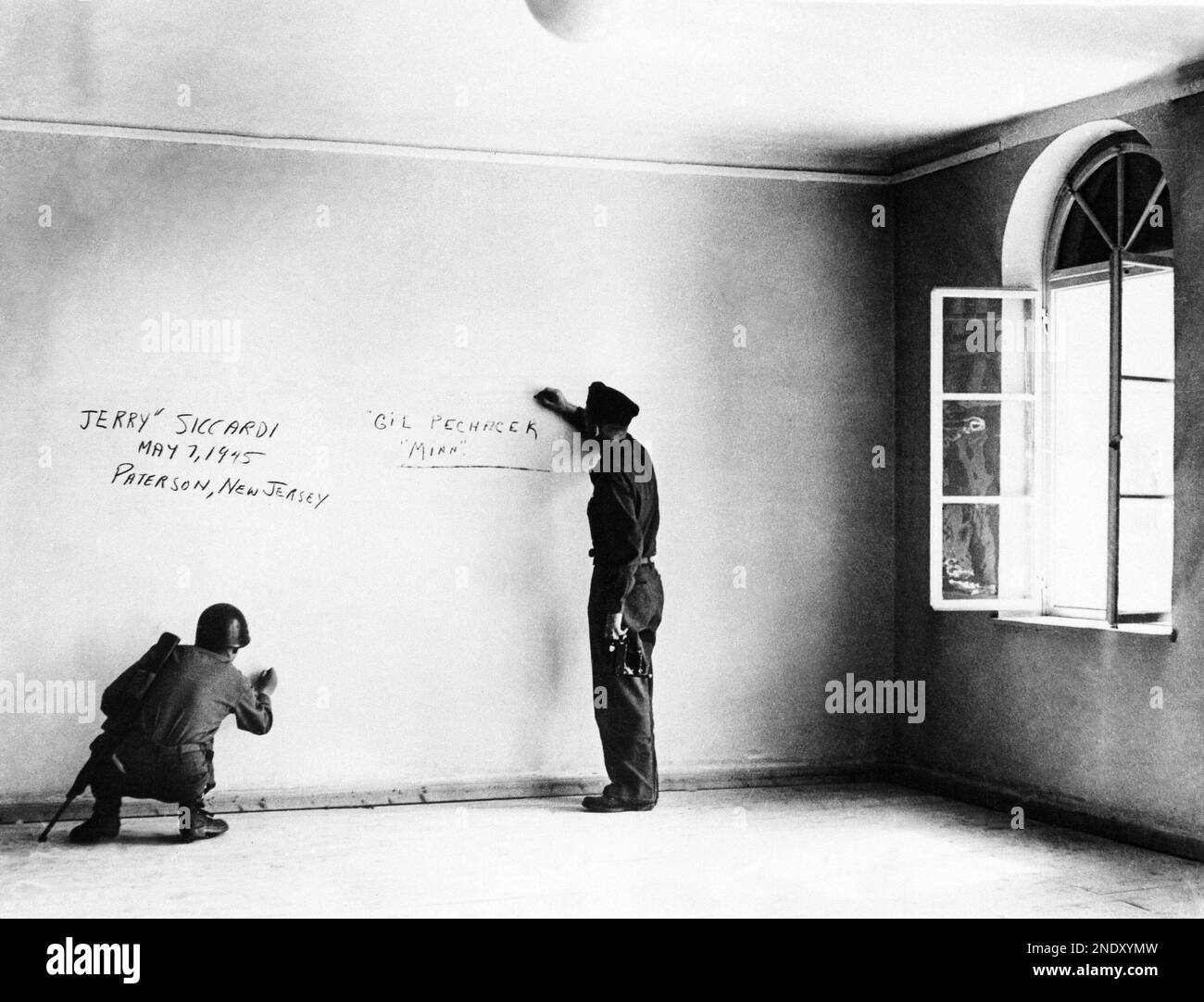 A couple of American soldiers write their names on the wall of the bedroom where Adolf Hitler was born in Braunau, Austria, June 14, 1945. The house has been re-modeled and Nazis used to stand in reverence before it. (AP Photo/Pool/INP) Banque D'Images
