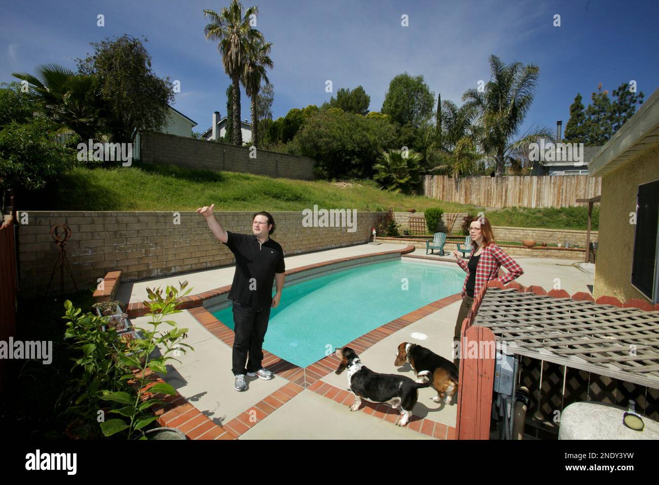 In this photo taken on Thursday, Apr. 15, 2010, new homebuyers Fred Archambault and his wife Amy, with their dogs, Taz and Fletch, enjoy their new home in Santa Clarita, Calif. They couldn't afford to buy in the West Hollywood neighborhood where they rented in for 10 years, so they moved 30 miles north to Santa Clarita and bought their house for $385,000. (AP Photo/Damian Dovarganes) Banque D'Images