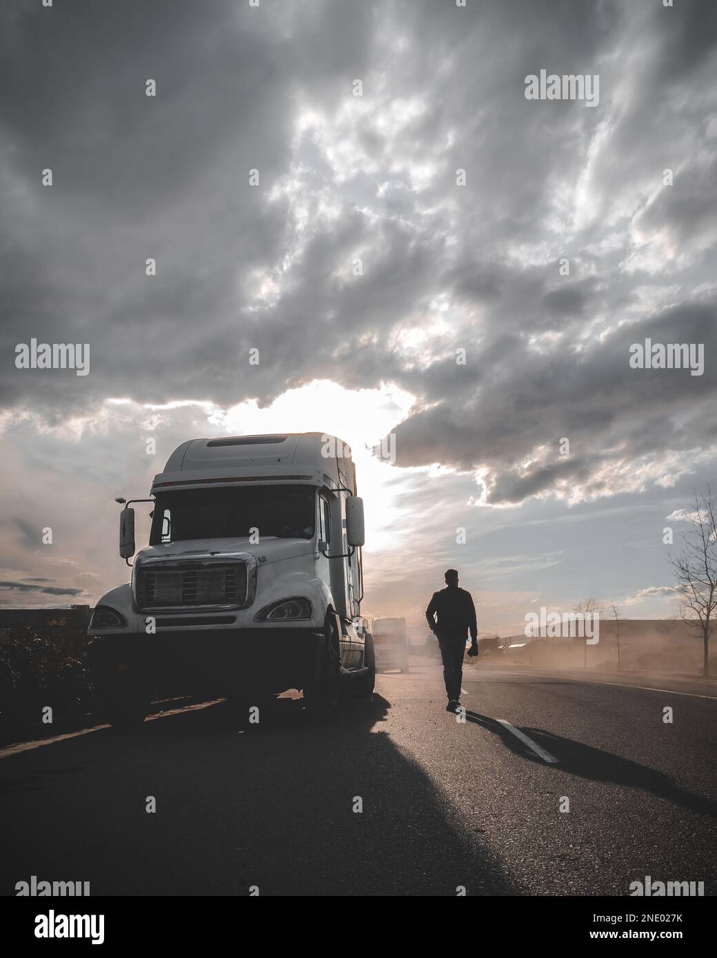 Homme solitaire marchant à côté d'un camion pendant le coucher du soleil Banque D'Images