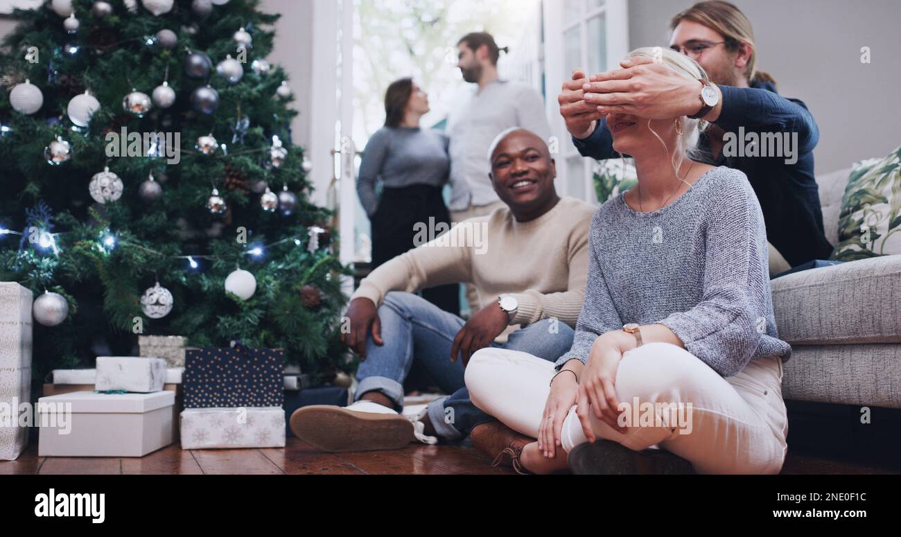 Moins sur le cadeau, plus sur l'amour donné avec. Une jeune femme reçoit un cadeau de Noël surprise de la part d'amis. Banque D'Images