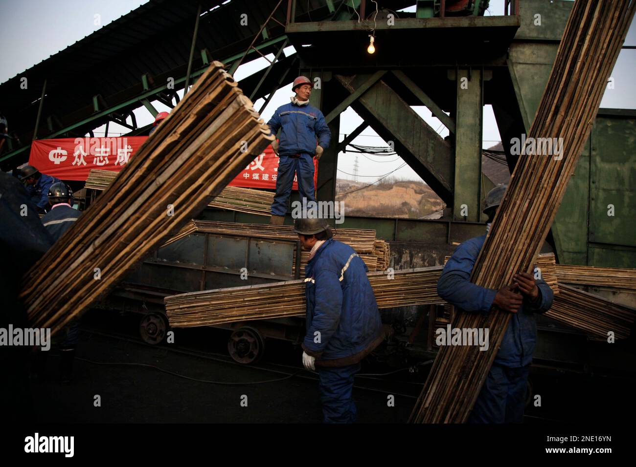 Coal miners carry bamboo platforms to be used to cross wet sections of the mine at Wangjialing Coal Mine in Xiangning county in north China's Shanxi province, Sunday, April 4, 2010. Rescue workers set up equipment and prepared Sunday to mount an operation to try to find survivors among 153 trapped miners in the mine, saying they have not given up hope more than one week after the mine flooded. (AP Photo/Ng Han Guan) Banque D'Images