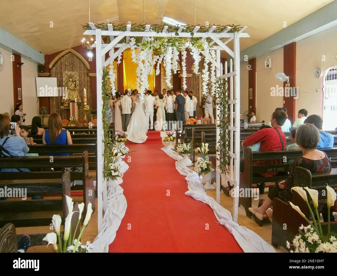 Mariée marchant dans l'allée de la chapelle tapis rouge lors d'un mariage philippin catholique. Banque D'Images