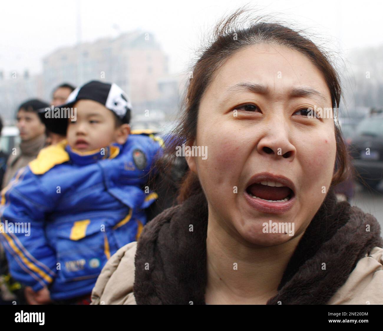 Li Xuemei, right, wife of Zhao Lianhai, shouts outside a court house as she is not allowed to enter to see her husband during a trial case in Beijing, Tuesday, March 30, 2010. Zhao Lianhai, who organized a support group for parents of children sickened in one of China's worst food safety scandals pleaded not guilty Tuesday to charges of inciting social disorder, his lawyer said. (AP Photo/Andy Wong) Banque D'Images