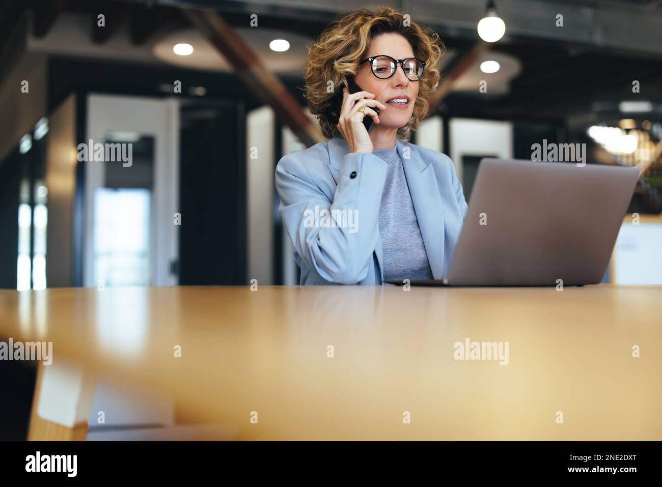 Appeler des clients sur un téléphone mobile. Femme d'affaires professionnelle regardant un écran d'ordinateur portable pendant un appel téléphonique. Femme d'affaires mature travaillant Banque D'Images