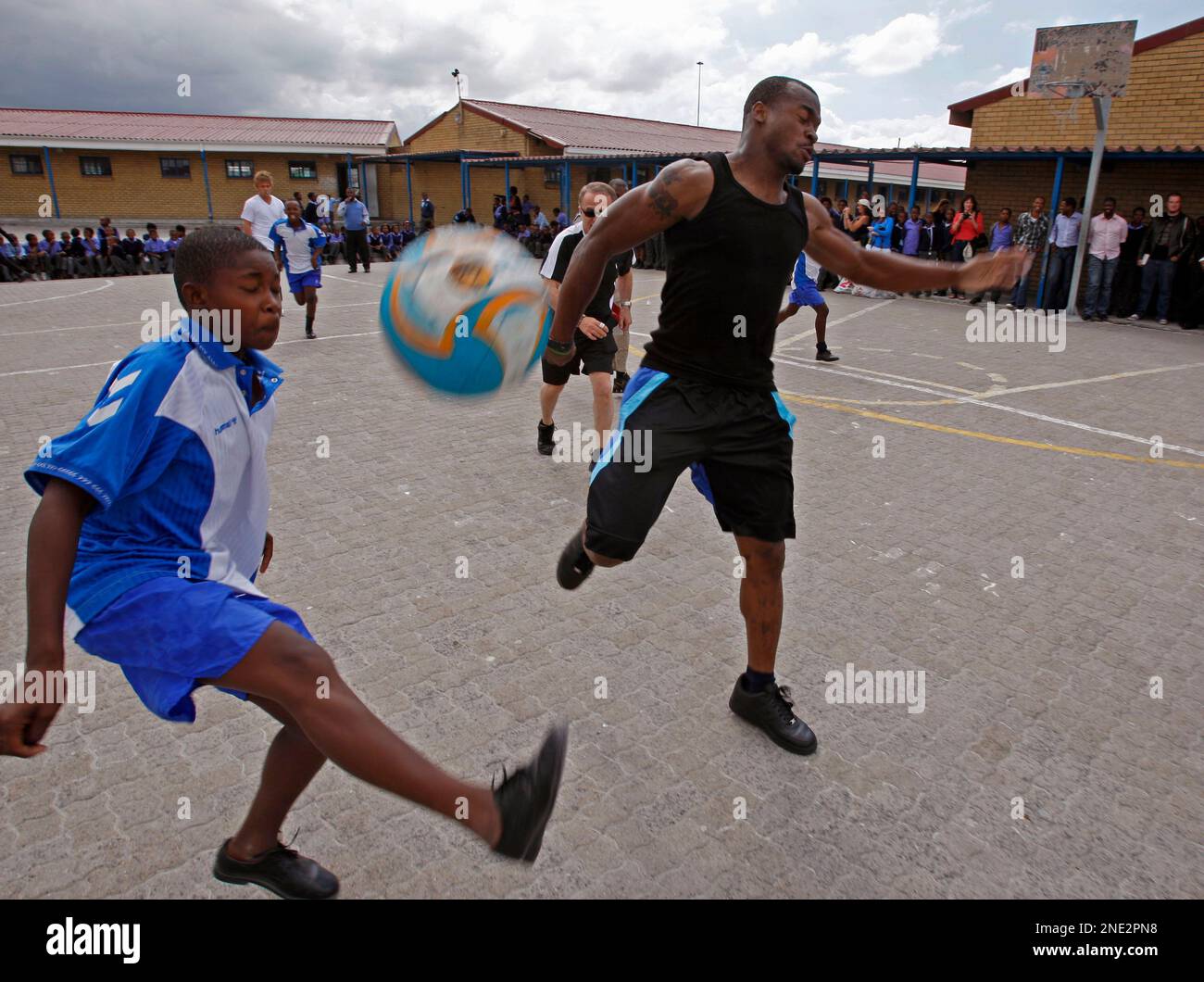 American NFL player Adrian Peterson, right, from the Minnesota Vikings, fights fore the ball during a friendly soccer game against school children from Mzamomhle Primary School in the township of Philippi on the outskirts of Cape Town, South Africa, Thursday, March 25, 2010. Four American NFL players are on a four day visit to the Western Cape to promote football. (AP Photo/Schalk van Zuydam) Banque D'Images