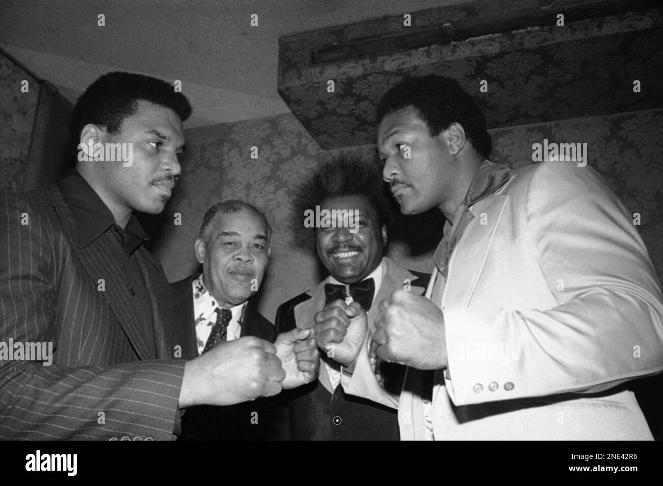 Former heavyweight boxing champ George Foreman, right, aims a baleful look at Jimmy Young, left, his opponent in a heavyweight bout slated for March 17 in Puerto Rico. The fight was announced on Tuesday, Feb. 15, 1977 at a New York press conference by fight promoter Don King, second from right, joined by former boxing great Joe Louis. (AP Photo/Marty Lederhandler ) Banque D'Images
