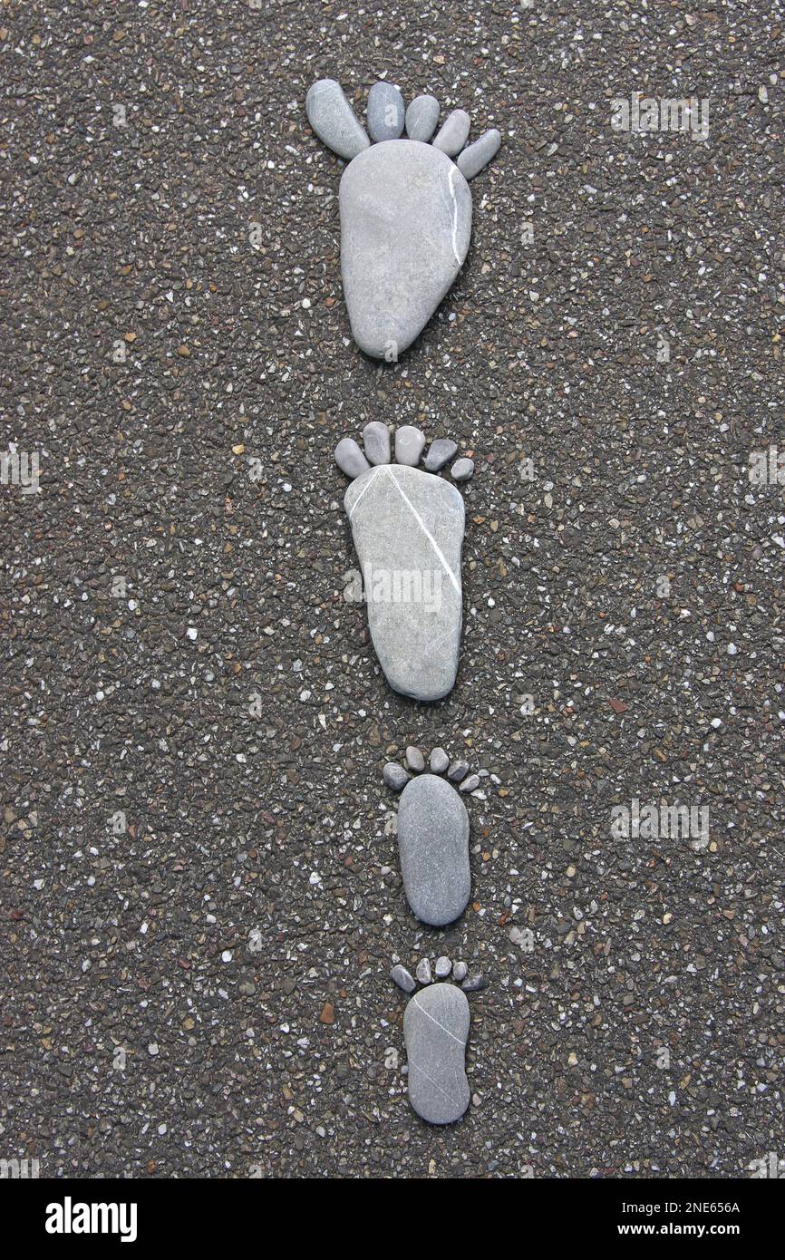 grands et petits pieds en pierre sur l'asphalte Banque D'Images