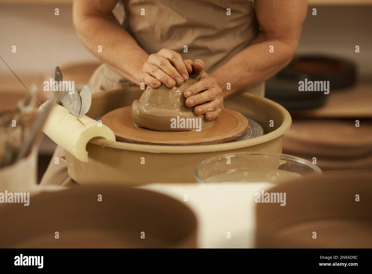 Céramiste tournant un morceau d'argile sur une roue dans un studio Banque D'Images