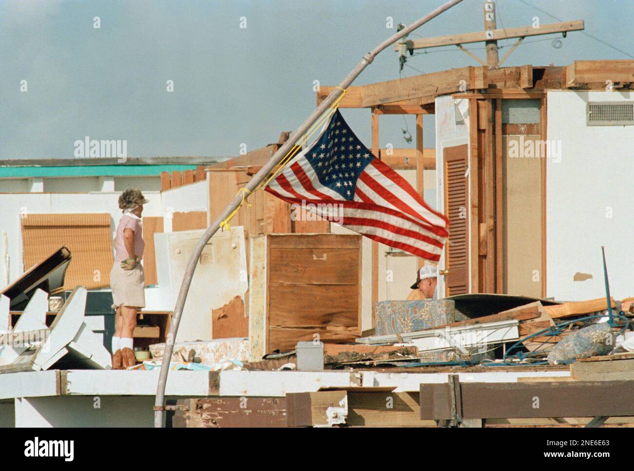 Bill and Floss Wiseman, Houston residents, fly the flag as they try to salvage belongings in their destroyed beach house on the west end of Galveston Island, Aug. 20, 1983. (AP Photo/David Breslauer) Banque D'Images