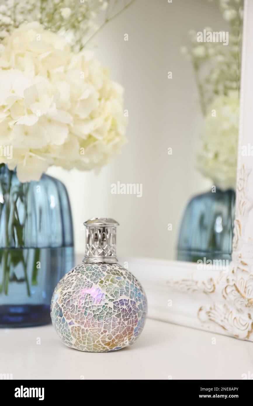 Lampe catalytique élégante avec beau bouquet sur table blanche près du  miroir. Intérieur confortable Photo Stock - Alamy
