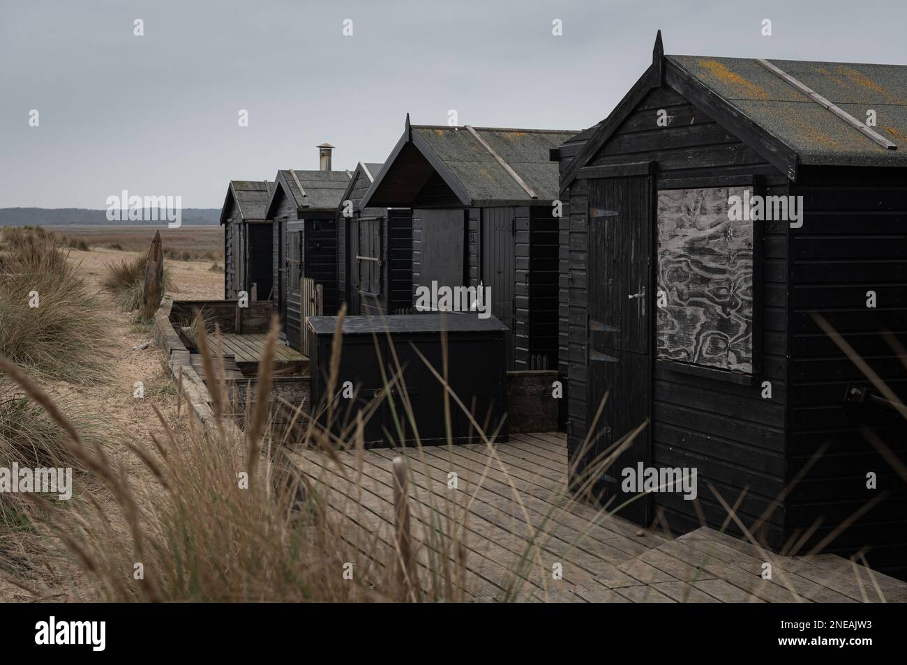 Cabanes de plage noires à Walberswick, Suffolk. Gris, moody. Banque D'Images