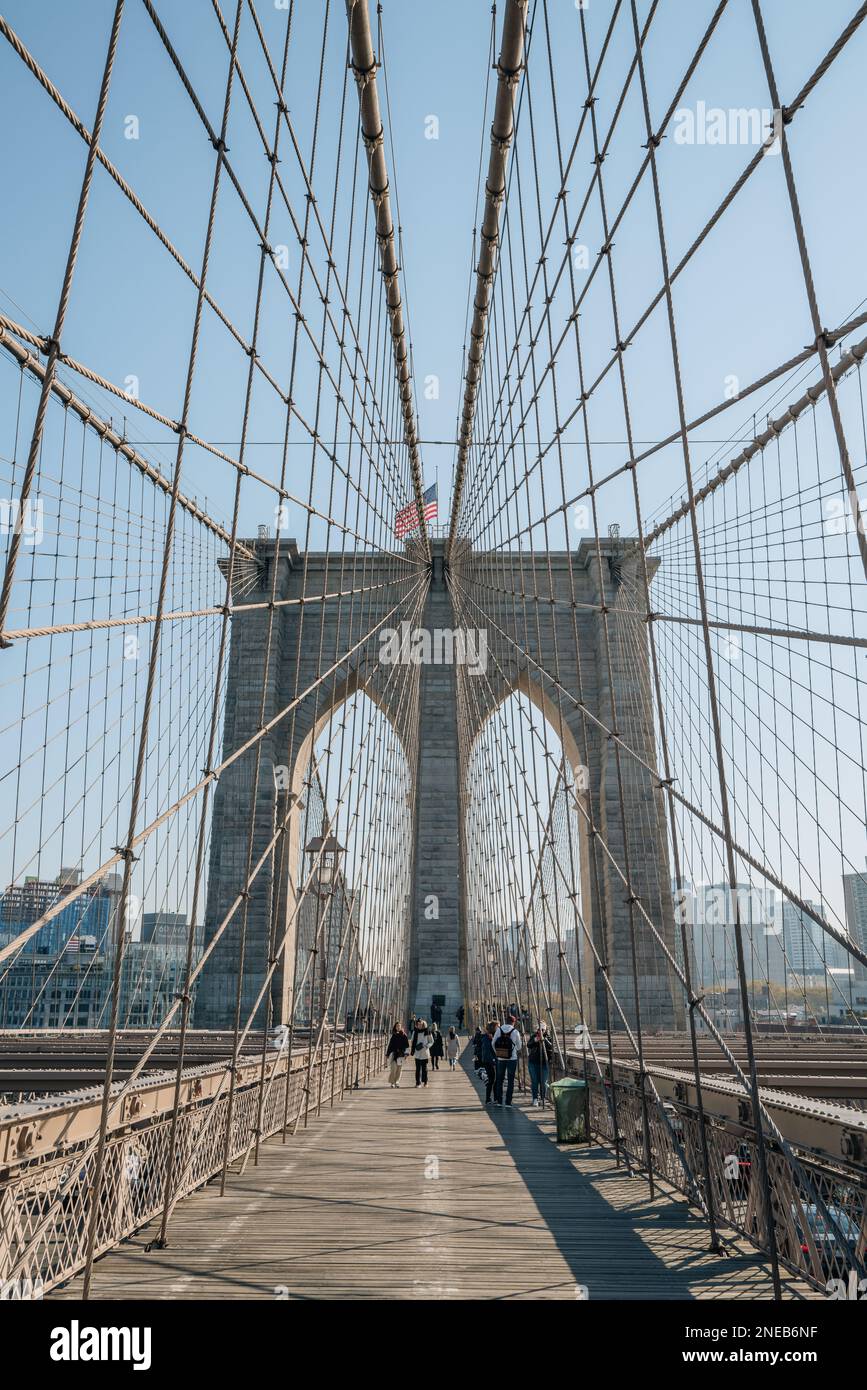 New York, Etats-Unis - 21 novembre 2022: Personnes marchant sur le pont de Brooklyn, un célèbre pont hybride à suspension par câble dans la ville de New York, sur un passage ensoleillé Banque D'Images