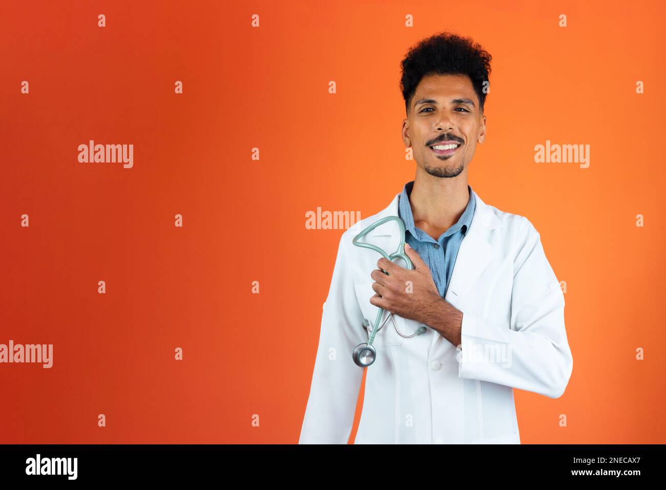 Jeune médecin ou vétérinaire noir avec stéthoscope tenant isolé sur Orange Banque D'Images