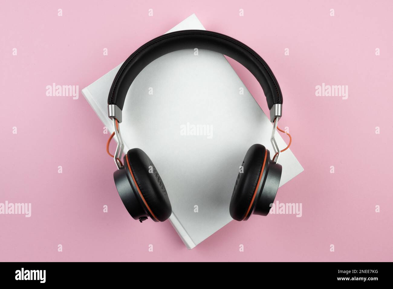 concept de livre audio, vue de dessus du casque stéréo sur le livre de couverture sur le bureau rose Banque D'Images