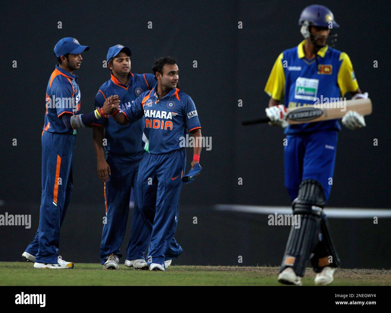 India's Shanthakumaran Sreesanth, left, and Suresh Raina, second left, congratulate teammate Amit Mishra, third left, on dismissing Sri Lanka's Chanaka Welegedara, unseen, as Suranga Lakmal walks by during the fifth one-day international cricket match of the tri-series in Dhaka, Bangladesh, Sunday, Jan. 10, 2010. Bangladesh, India and Sri Lanka are competing in the one-day international tri-series that started Monday. (AP Photo/Aijaz Rahi) Banque D'Images