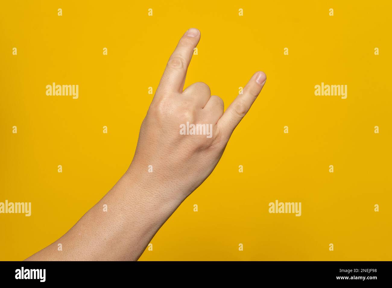 Le gros plan de la main masculine sur un fond jaune montre le mouvement de la main. Rock'n'roll. Isoler Banque D'Images