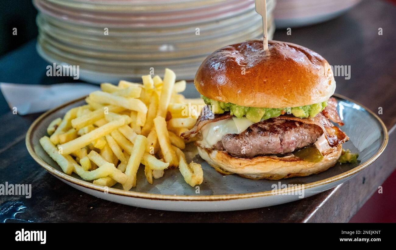 Un hamburger de bœuf fraîchement grillé au Guacamole servi à côté de frites Banque D'Images