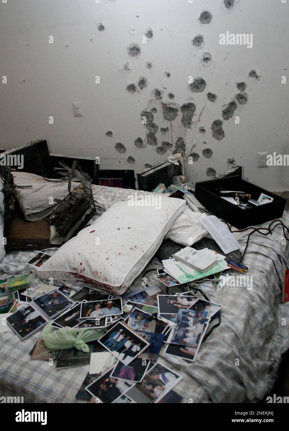 A wall with bullet holes is seen next to photos and other things sitting on a bed in an apartment in Cuernavaca, Mexico, Thursday, Dec. 17, 2009. A Mexican navy official said that alleged drug cartel chief Arturo Beltran Leyva and three members of his cartel were slain Wednesday inside the apartment during a shootout with sailors. (AP Photo/Antonio Sierra) Banque D'Images