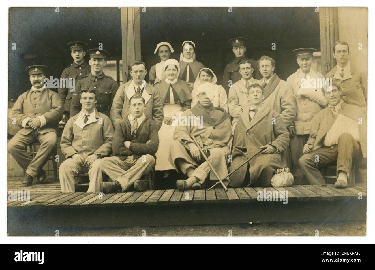 Carte postale originale de la première Guerre mondiale de soldats convalescents blessés britanniques certains avec des bandages, l'un a une blessure à l'oeil et à la tête, d'autres peuvent avoir un choc obus / TSPT. Certains portent des uniformes bleus de l'hôpital, d'autres manteaux, devant un hôpital de campagne, un établissement médical derrière les lignes de front, ou un hôpital de base à l'arrière en France peut-être, ou un hôpital de réserve au Royaume-Uni Un soldat du York and Lancaster Regiment se tient au milieu du groupe, peut-être ces hommes sont de son régiment. Il y a plusieurs soldats du Royal Army Medical corps présents ainsi que des infirmières, vers 1915-1918. Banque D'Images