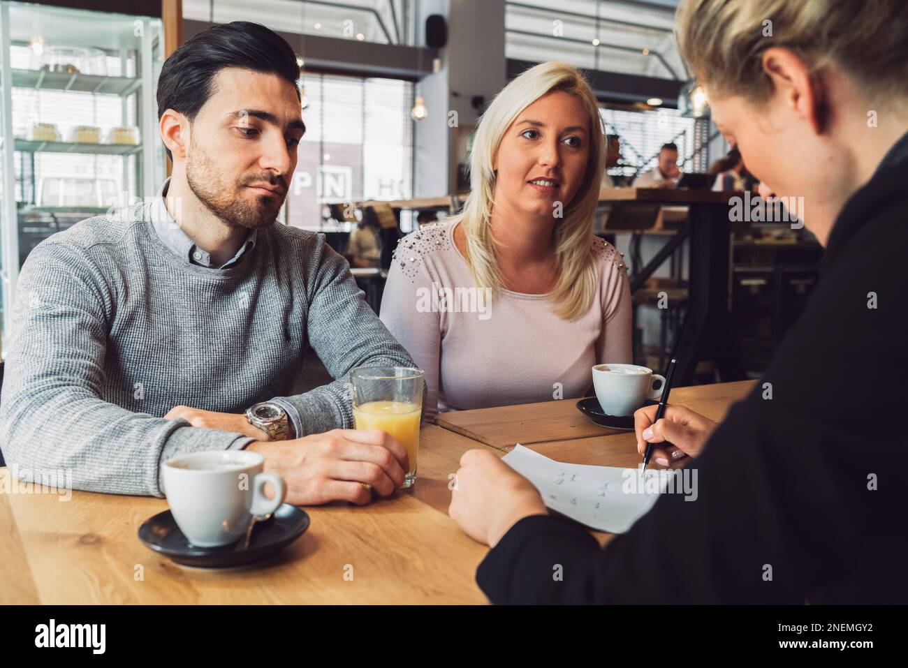 Jeune couple sur une réunion ayant un peu de café avec leur agent immobilier Banque D'Images