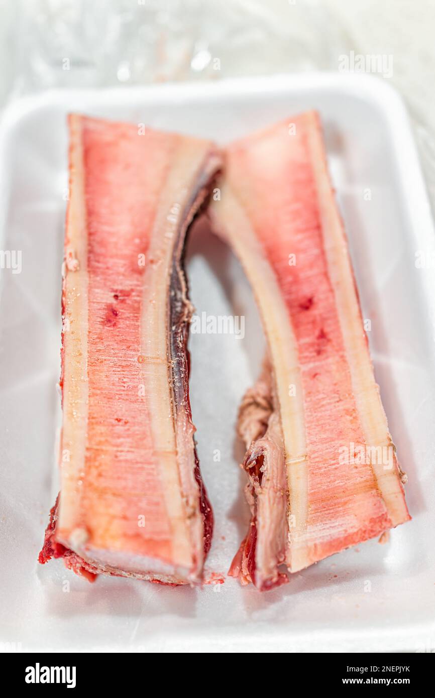 OS de moelle de bœuf crus non cuits pour rôtir macro gros plan avec texture de graisse rouge rose sur plateau en plastique et personne comme nourriture à la mode Banque D'Images