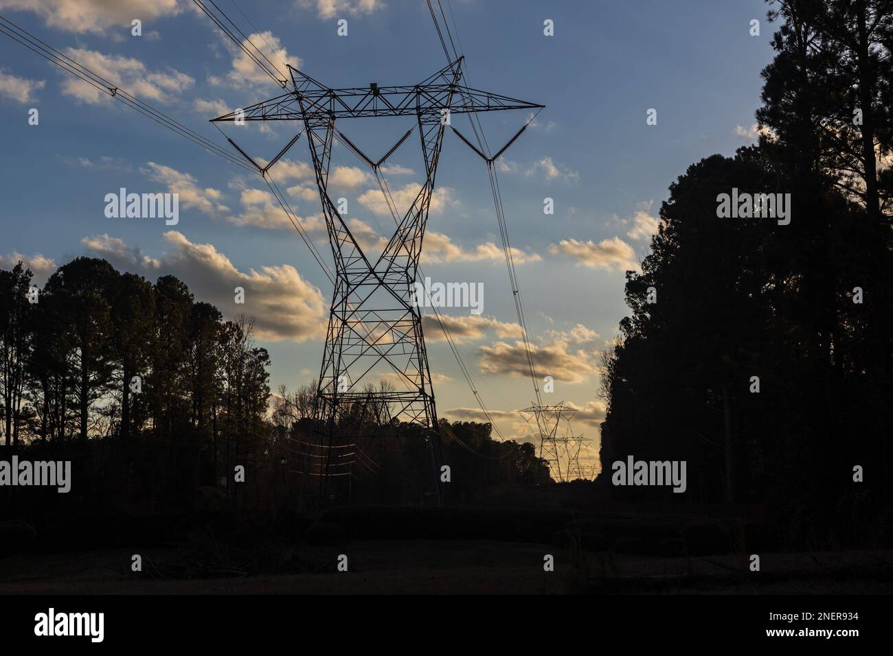 Silhouette de tour de transmission d'électricité au crépuscule contre le ciel bleu et les nuages moelleux. Banque D'Images