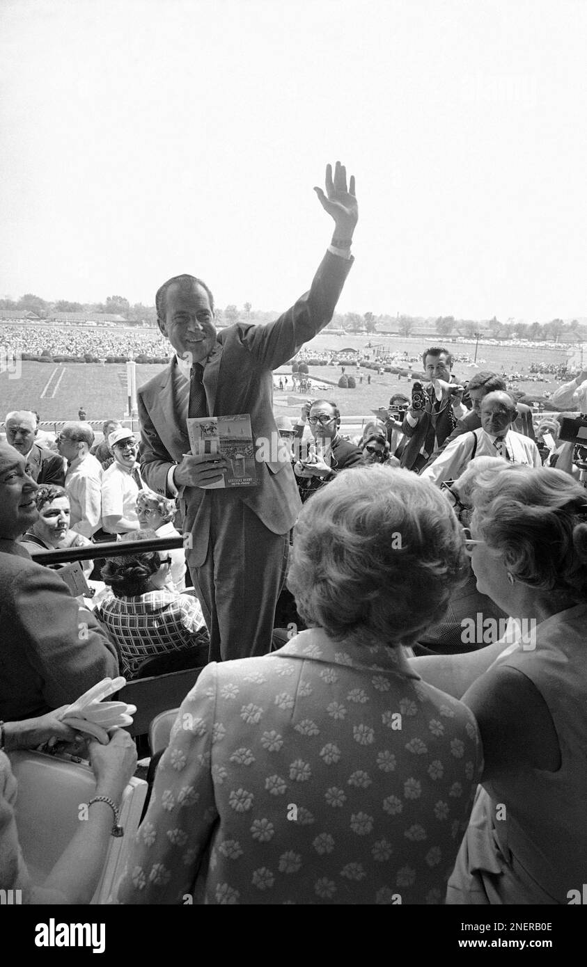 President Richard M. Nixon, clutching his program, turns to wave from his seat at Churchill Downs in Louisville, Kentucky on May 3, 1969, where he will view the 95th running of the Kentucky Derby. (AP Photo) Banque D'Images