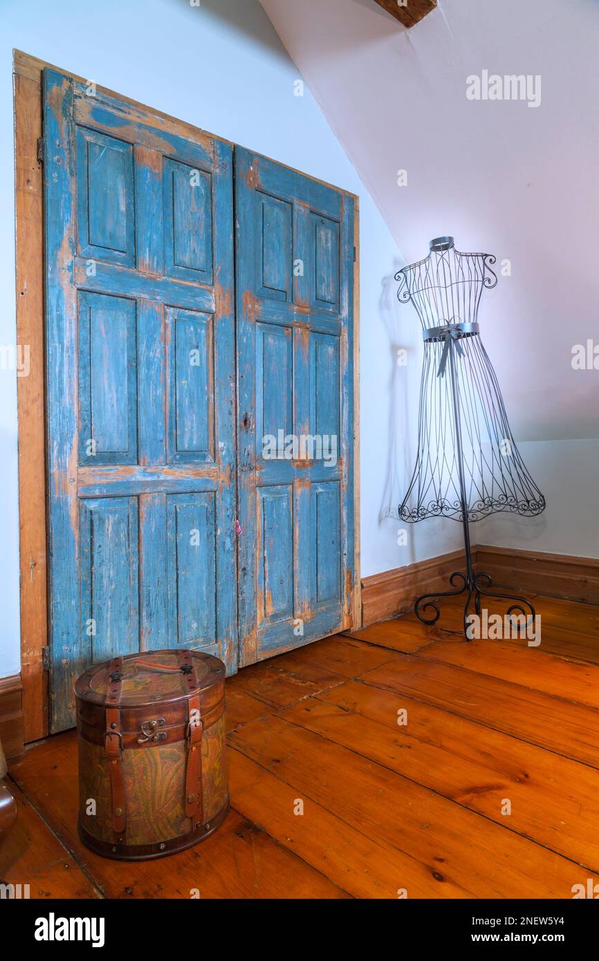 Vieilles portes de placard en bois turquoise, boîte à chapeau antique et robe en métal en fer forgé noir forment mannequin dans la chambre principale à l'étage dans la vieille maison de 1820. Banque D'Images