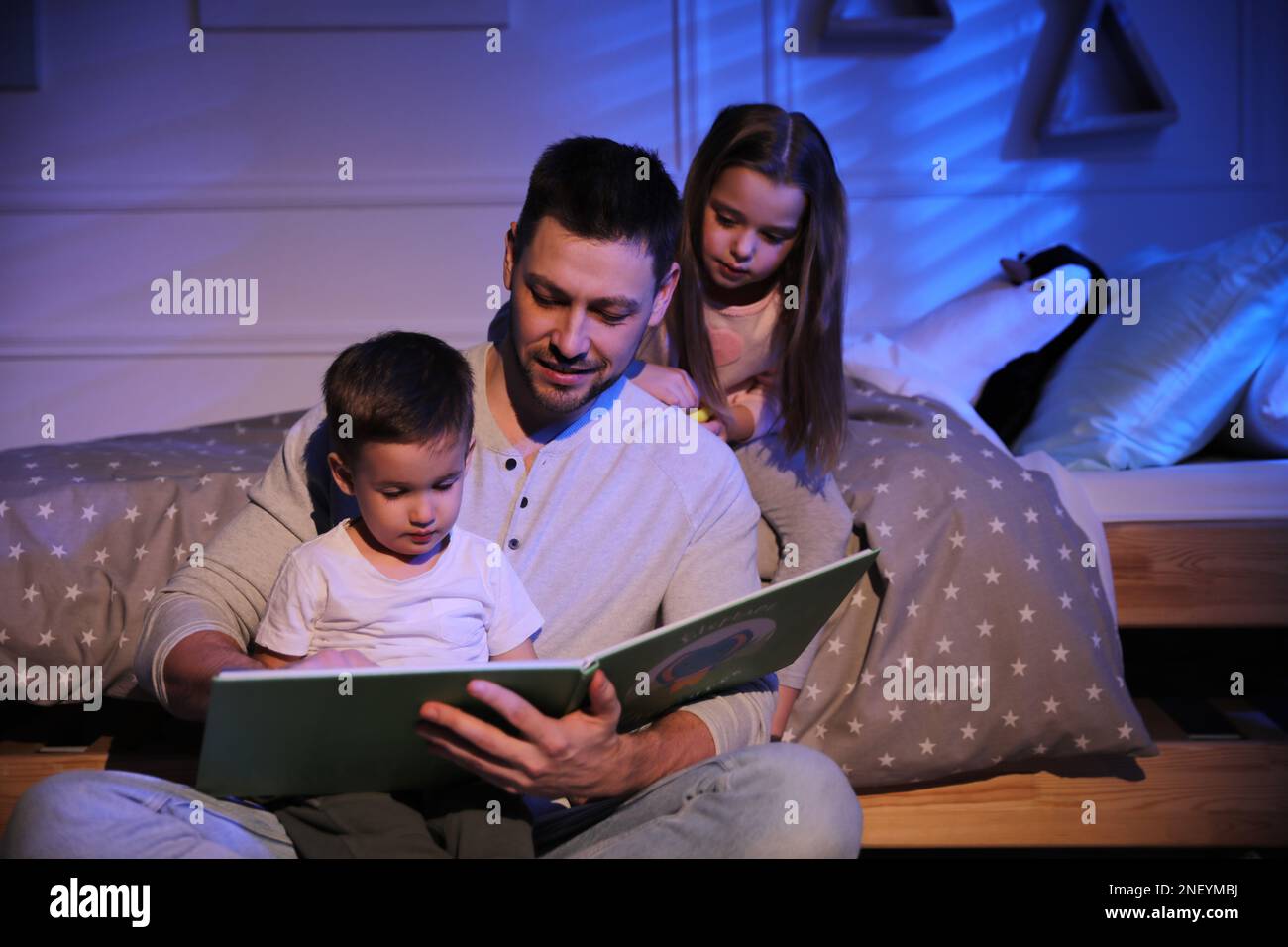 Père lisant l'histoire du coucher à ses enfants à la maison Banque D'Images