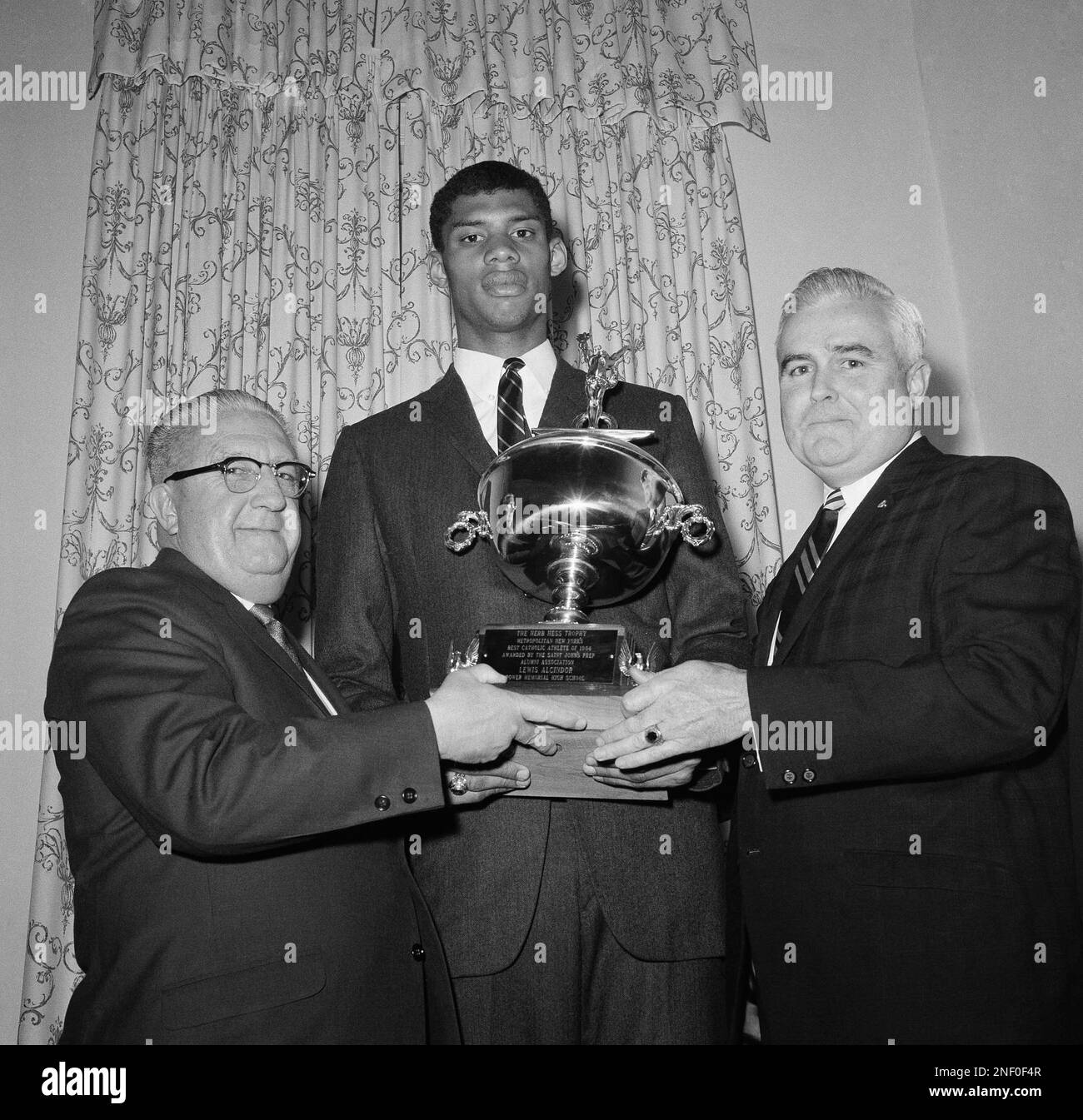 Lew Alcindor of Power Memorial High School, second from left, poses at the 19th annual Prep Alumni Banquet at Garden City, N.Y., on March 27, 1967. Alcindor, known as Karem Abdul Jabbar, was awarded the third annual Herb Hess Trophy as the outstanding Catholic high school athlete in the metropolitan area. From left: Herb Hess, Athletic Coach for St. John’s prep for over 30 years; Alcindor; and Desmond O’Connor, President of St. John’s Prep Alumni Association who made the presentation. (AP Photo)/Matty Zimmerman) Banque D'Images