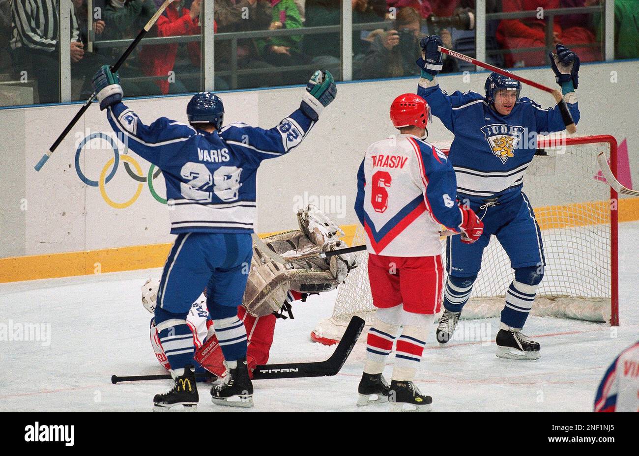 Finland’s Mika Alatalo, right, celebrates the goal he scored against Russian goalkeeper Valeri Ivannikov (on ice) giving Finland a 2-0 lead over Russia, while Finland’s Petri Varis raises his arms in the first period of their bronze medal game at the Olympics in Lillehammer, Saturday, Feb. 26, 1994. At center is Russia’s Vladimir Tarassov. The score was 2-0 to Finland at the end of the first period. (AP Photo/Denis Paquin) Banque D'Images