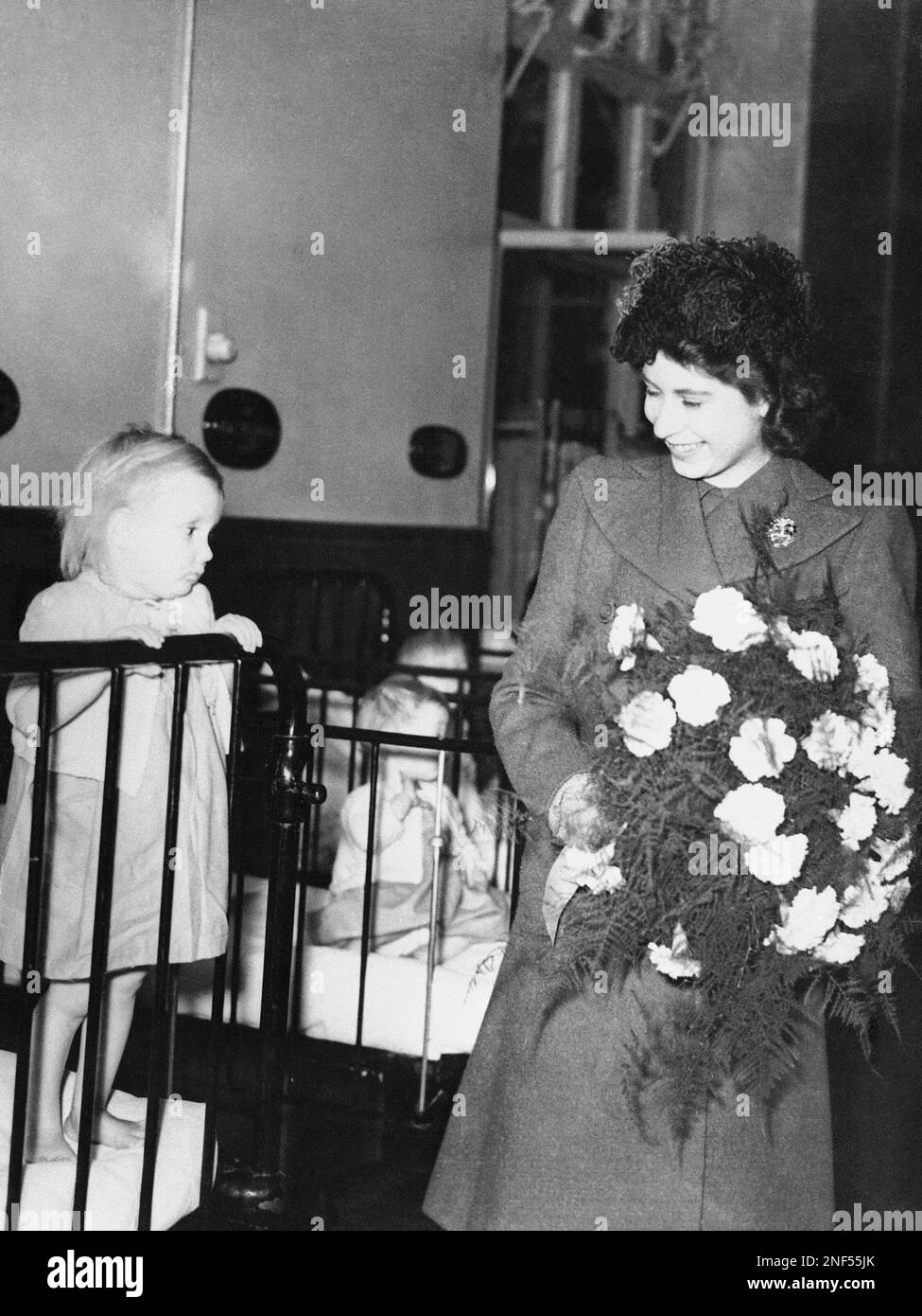 Princess Elizabeth (right) speaks to a young patient, Doreen Collins, 3, during a visit to the Royal Alexandra Children's Hospital at Brighton, England on Dec. 4, 1945, to participate in a ceremony officially opening new wings of the hospital. (AP Photo) Banque D'Images