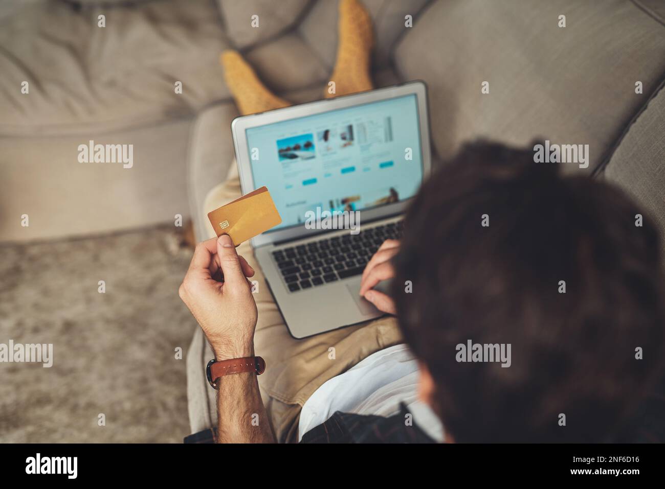 Les achats en ligne sont tellement plus pratiques. un homme méconnaissable utilisant son ordinateur portable et sa carte de crédit tout en se relaxant sur un canapé à la maison. Banque D'Images