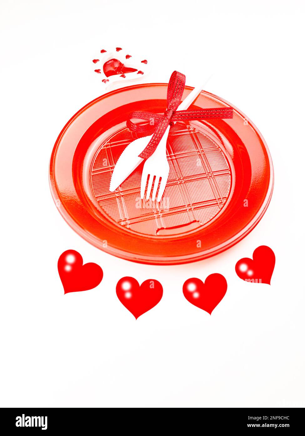 Menu des fêtes pour la Saint-Valentin. Assiette en plastique et couverts. Contour des coeurs sur fond blanc. Banque D'Images