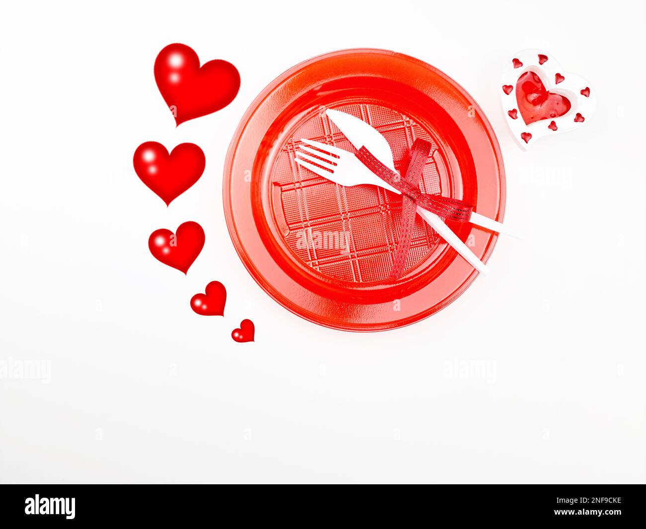 Menu des fêtes pour la Saint-Valentin. Assiette en plastique et couverts. Contour des coeurs sur fond blanc. Banque D'Images