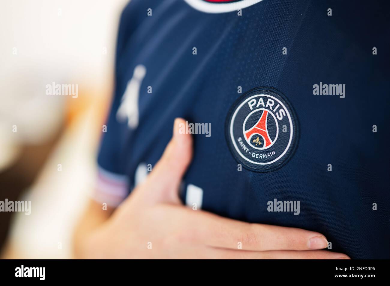 Ternopil, Ukraine - février, 2023: Garçon mis la main sur le coeur, port de l'uniforme de club de football PSG Paris Saint Germain. Banque D'Images