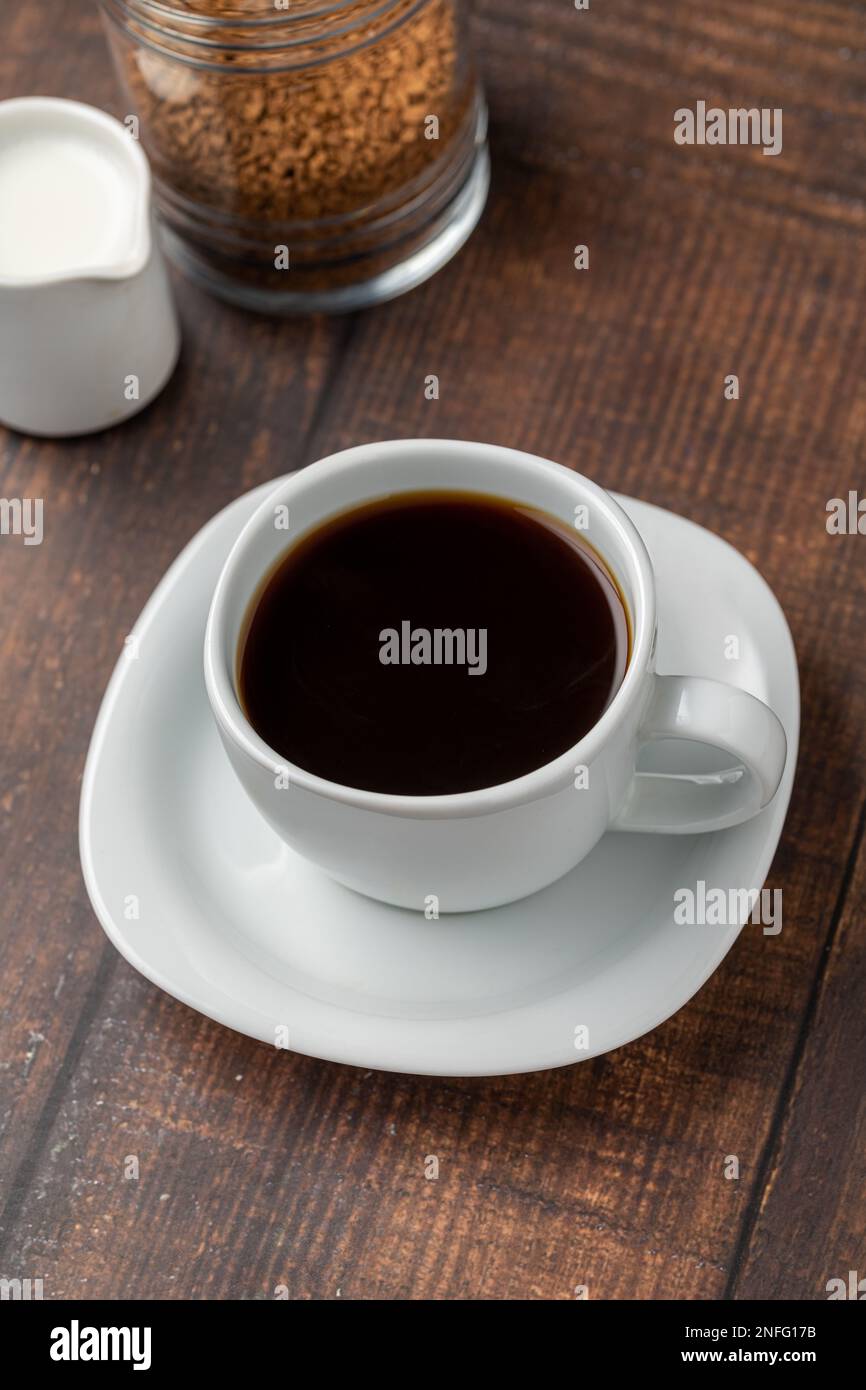 Café instantané ou granulé dans une tasse blanche sur une table en bois Banque D'Images