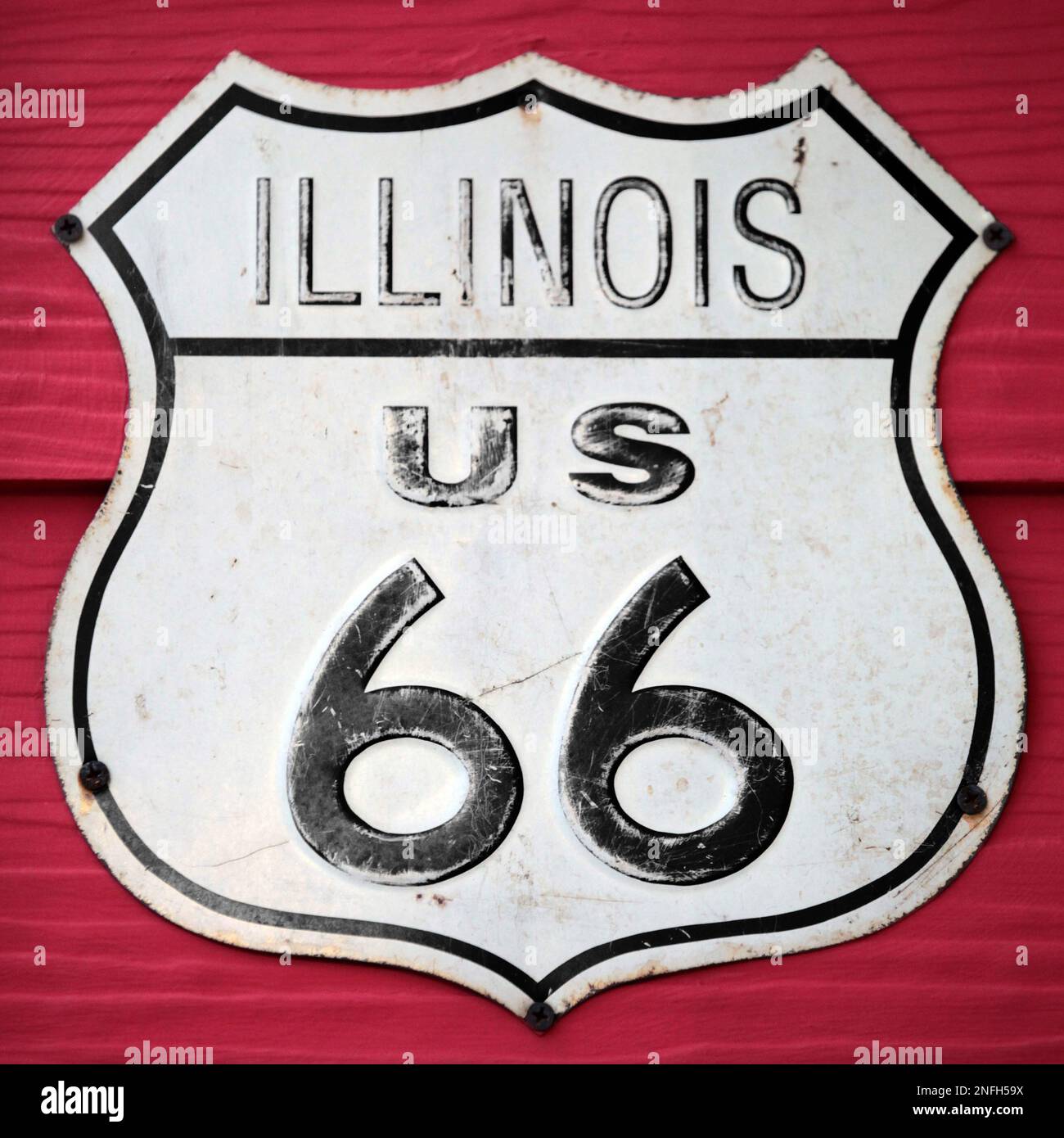 Gros plan sur un panneau de route Illinois US 66 vissé sur un mur en bois peint en rouge. Banque D'Images