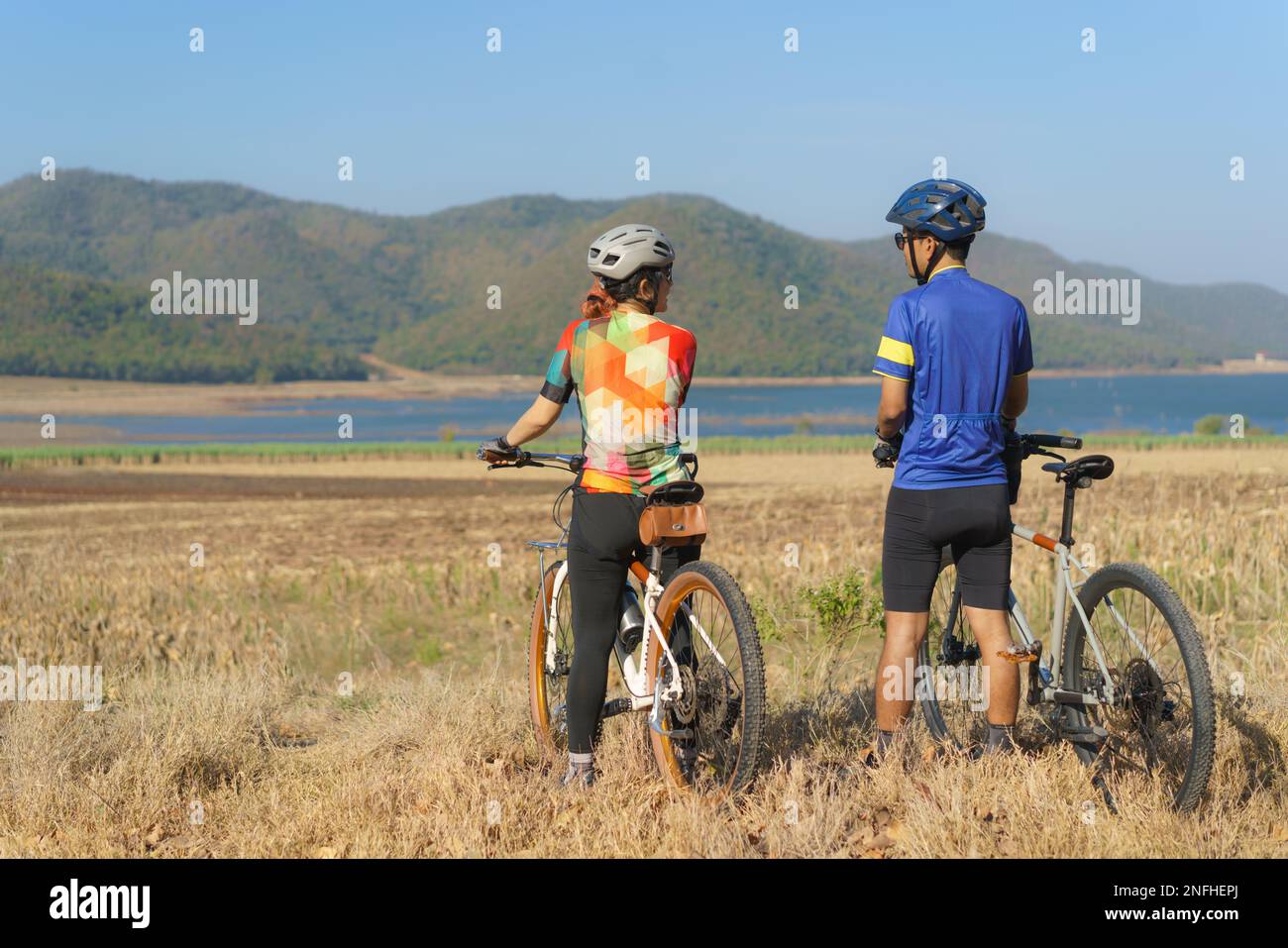 Couple cycliste asiatique regardant la vue sur le lac et la montagne et bavardant tout en prenant une pause de la promenade en vélo le matin Banque D'Images