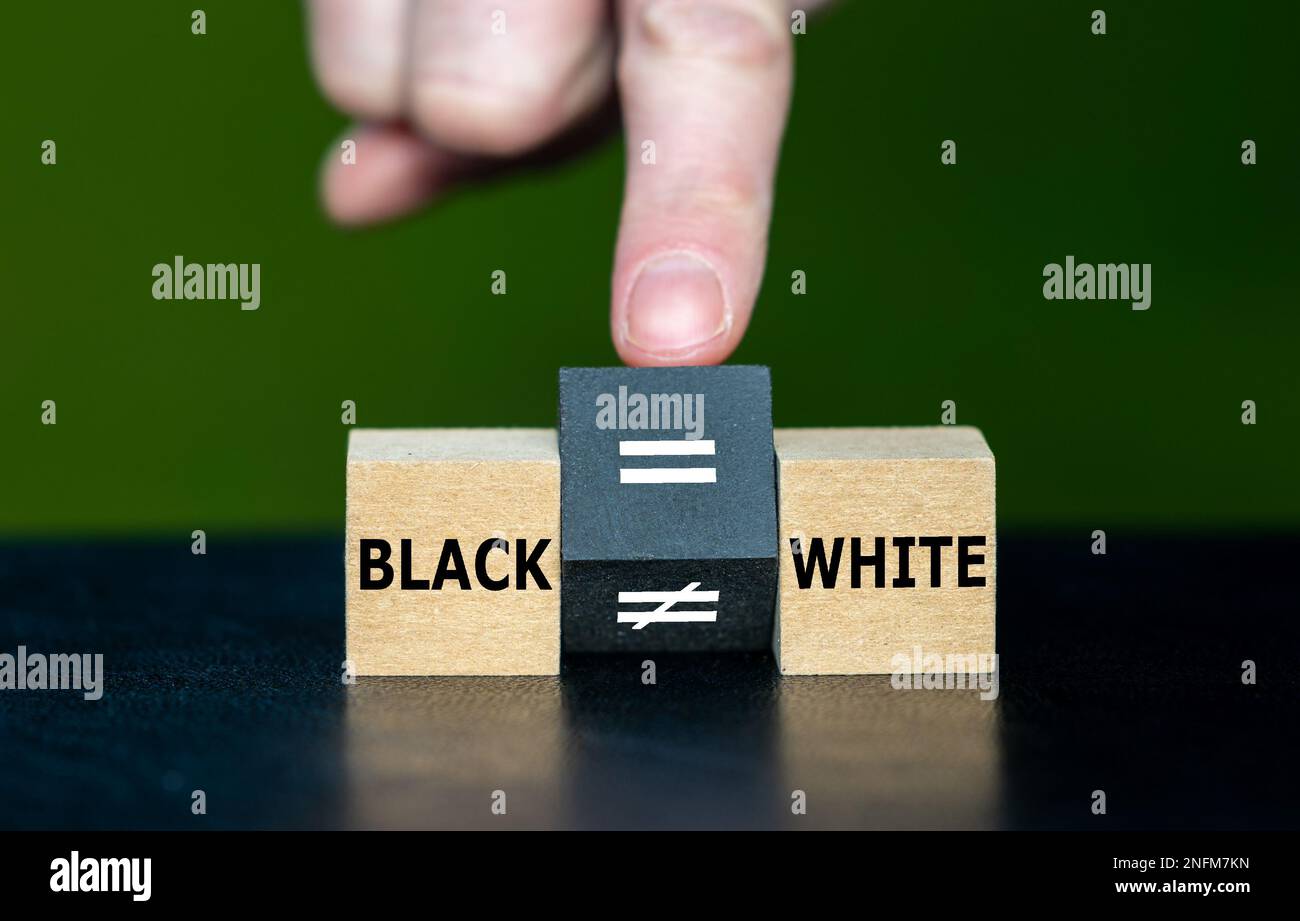 Symbole pour l'égalité des droits des personnes avec différentes couleurs de peau. La main tourne le cube en bois et change le signe inégal en signe égal. Banque D'Images