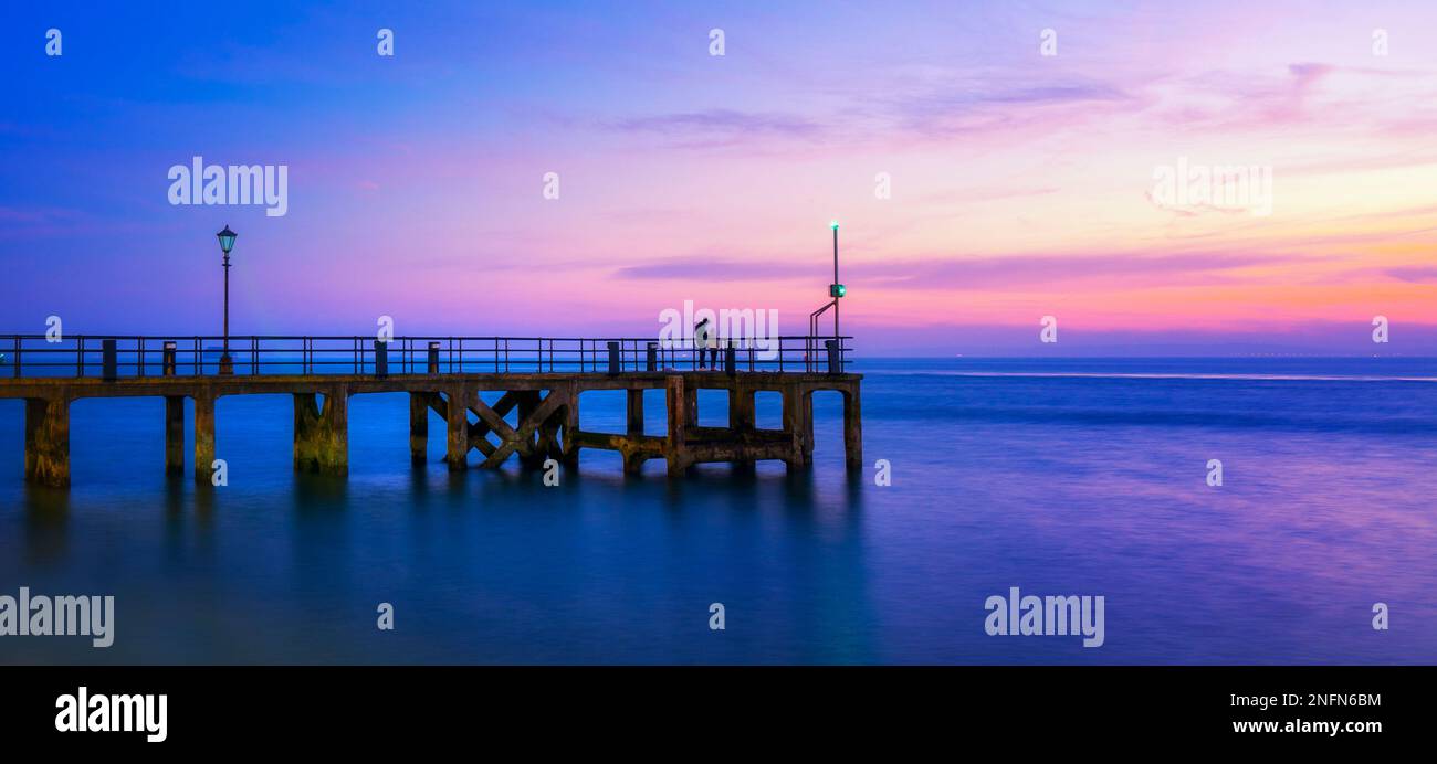 Homme pêchant sur la jetée de victoria, southsea, au coucher du soleil. Banque D'Images